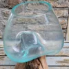 Handgemaakte bolvaas van gerecycled glas op wortelhout